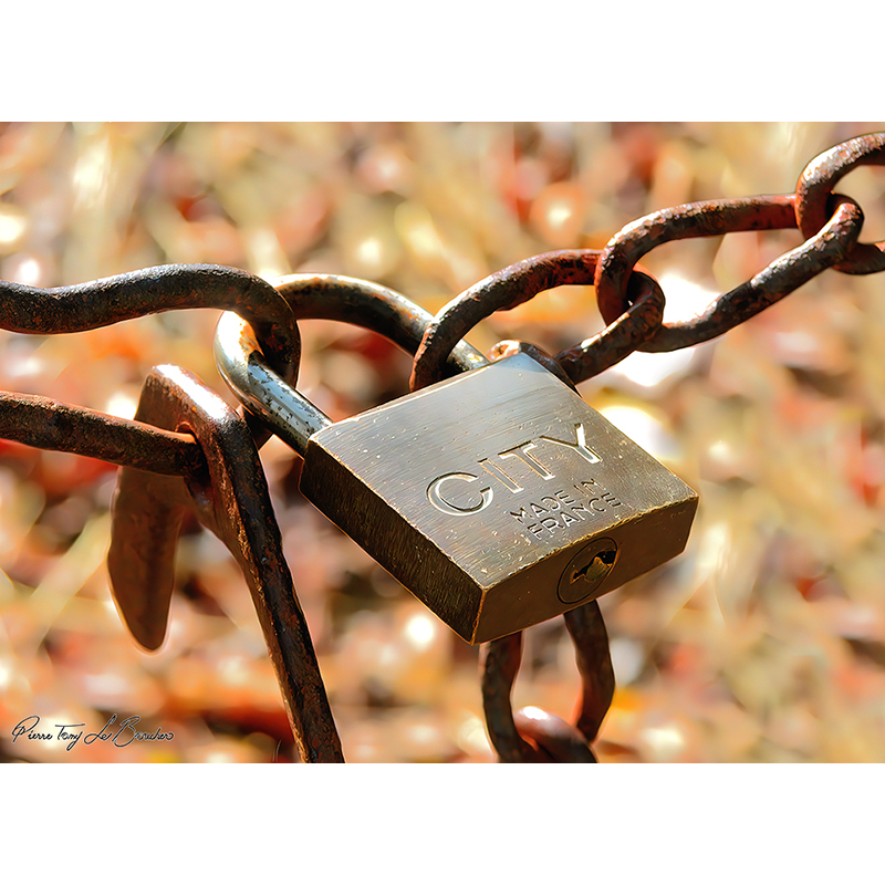 Cadenas métallique relativement préservé suspendu à une chaîne fortement rouillée, œuvre photographique de Pierre Tomy Le Boucher.
