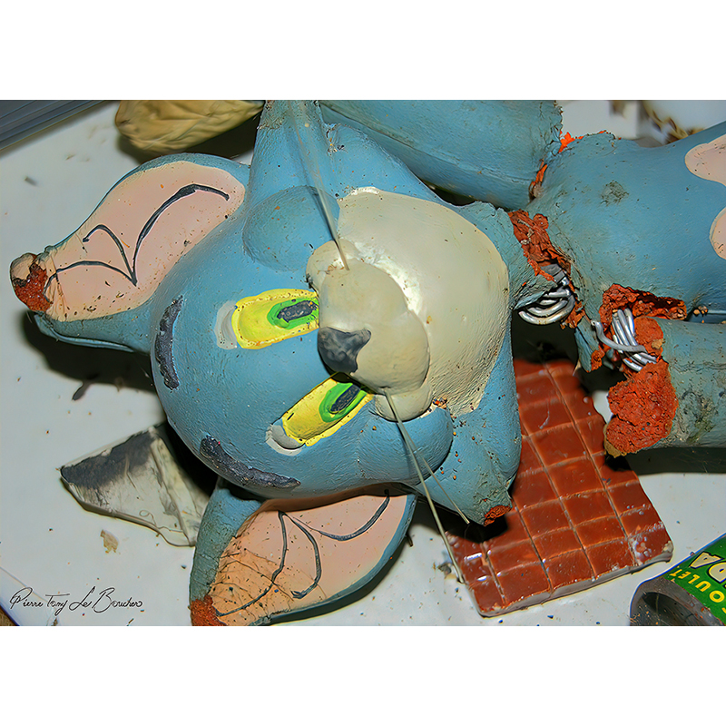 Ancienne figurine de chat bleu en mousse, déchirée et abîmée, laissant apparaître sa mousse orangée et son armature métallique intérieure, œuvre photographique de Pierre Tomy Le Boucher.