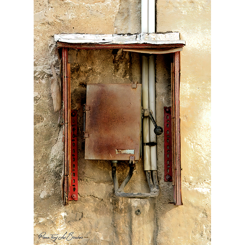 Ancienne installation électrique encastrée dans un mur très altéré, avec coffret métallique oxydé, câbles, gaines et éléments rouges, œuvre photographique de Pierre Tomy Le Boucher.