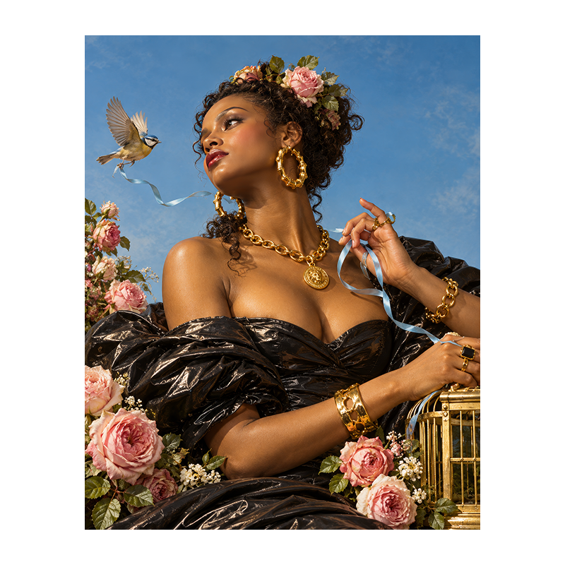 Jeune femme en robe noire et bijoux dorés parmi les roses, tenant un ruban bleu tandis qu’un oiseau s’envole près d’une cage dorée.