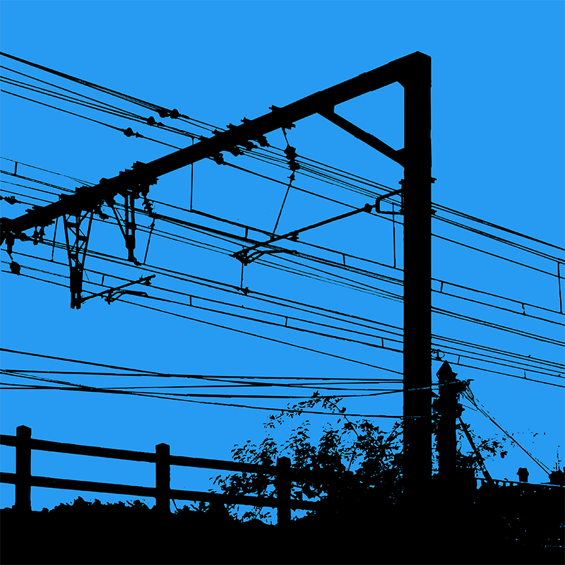 Silhouettes noires d’un réseau de caténaires, d’une structure ferroviaire et de végétation sur un ciel bleu uniforme.