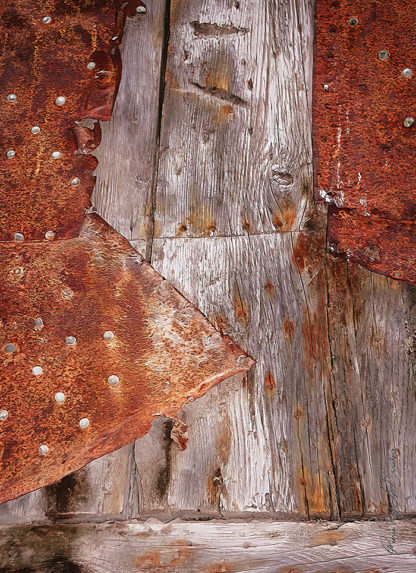Détail d'une réparation sur une porte en bois possédant les stigmates du temps et de l'usage.
