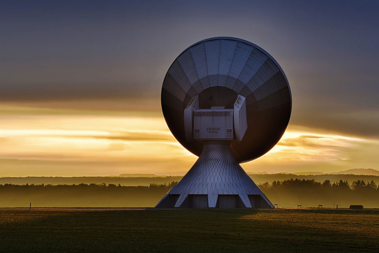 Prise de vue de nuit d'une antenne satellite parabolique pointant vers le ciel et diffusant des émissions de communication